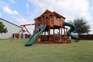 American redwood playset in Spring, Texas, Ticonderoga Tri-Level, redwood wooden forts, twister slide, swings, rave slide, and rock wall