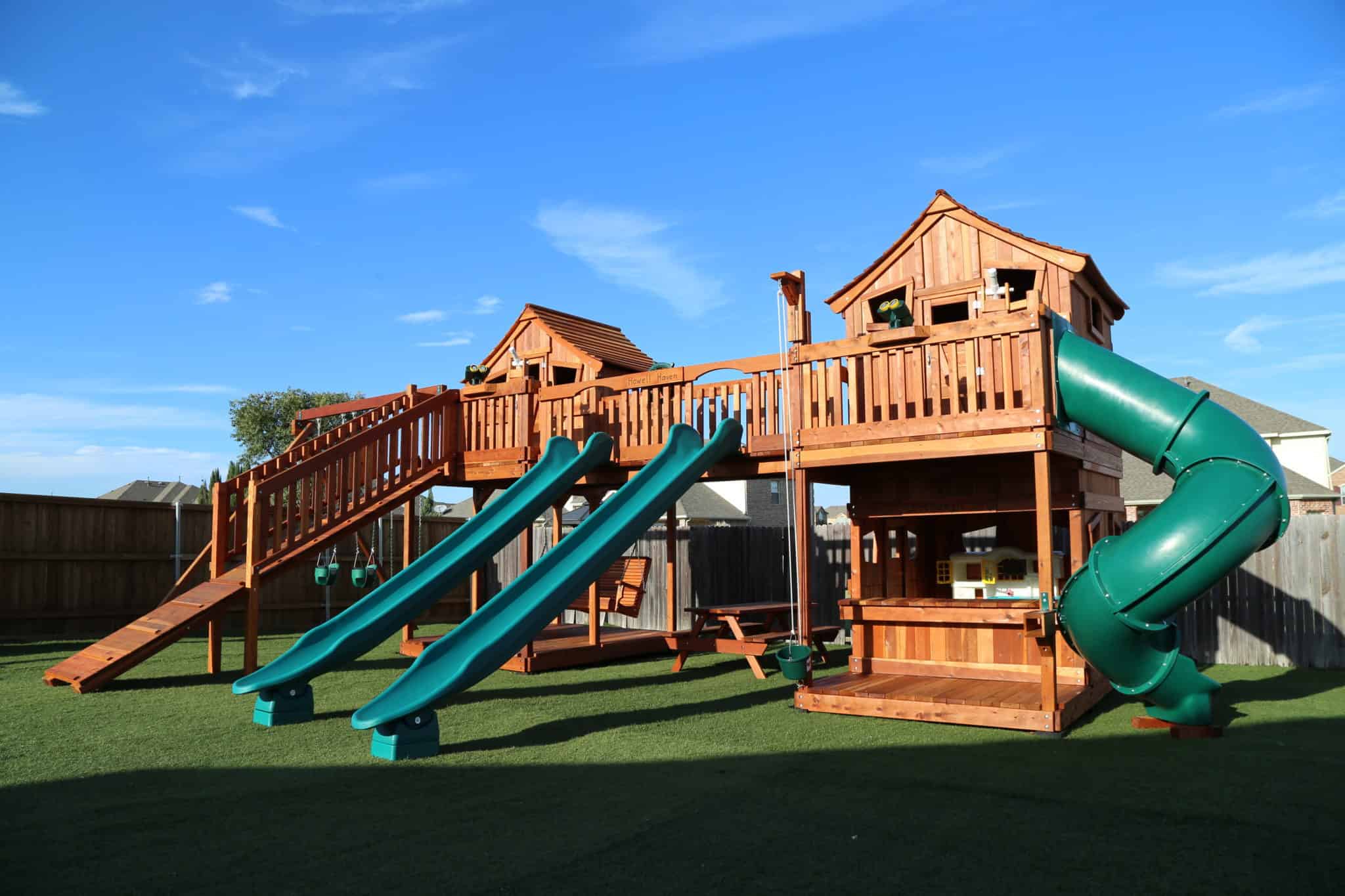 Saginaw, Texas, Bridged redwood playset with swings and adult porch swing. Spiral slide and rocket slides accessorize this fun backyard swing set.