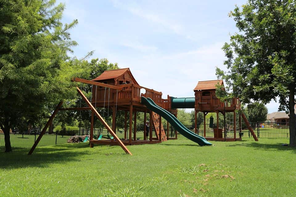 Spring, Texas, customer playset shown with redwood playset with bridge and cabins connected to crawl tube and slides and swings