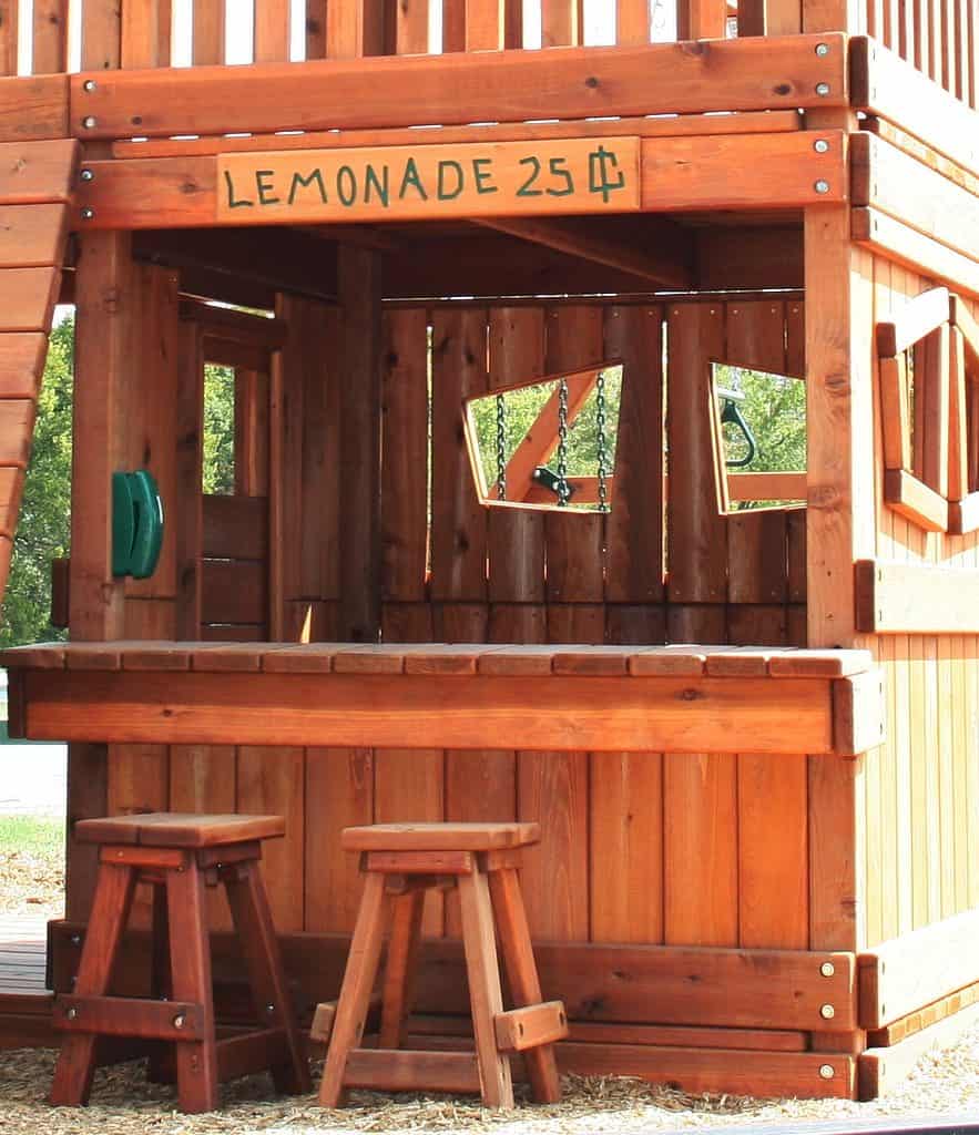 The Lemonade stand addition can be turned into a puppet show stage easily with a curtain. additions swing set components, lemonade stand with counter, sign, and stools built into the lower cabin of this redwood swing set