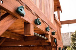 green climbing rocks attached horizontally to wooden swing set in dallas and shown with chin up bar swing set accessory