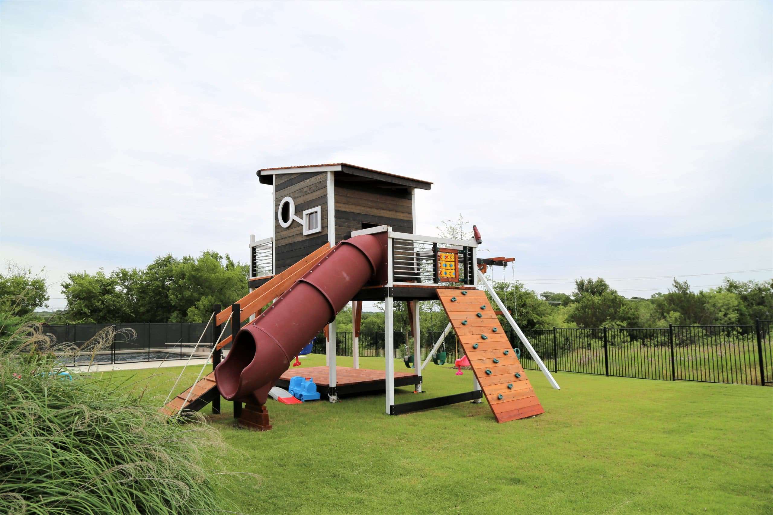 modern playset, new swing sets, with slant roof and artsy windows, tube slide, rock walls, swings