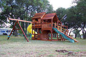 fun shack trilevel playset, multilevel swing set, yellow spiral slide, pirate flag, and adventure ramp