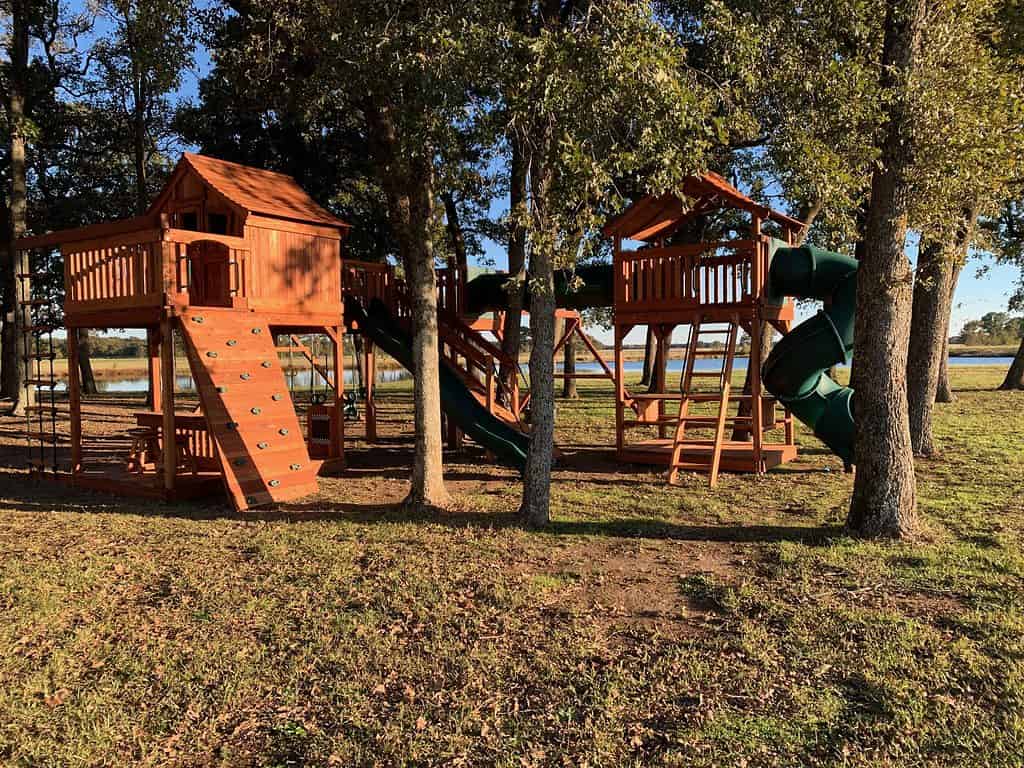 unique spaces are not a problem for backyard fun factory. this bridged playset has a wide open space with trees all around.