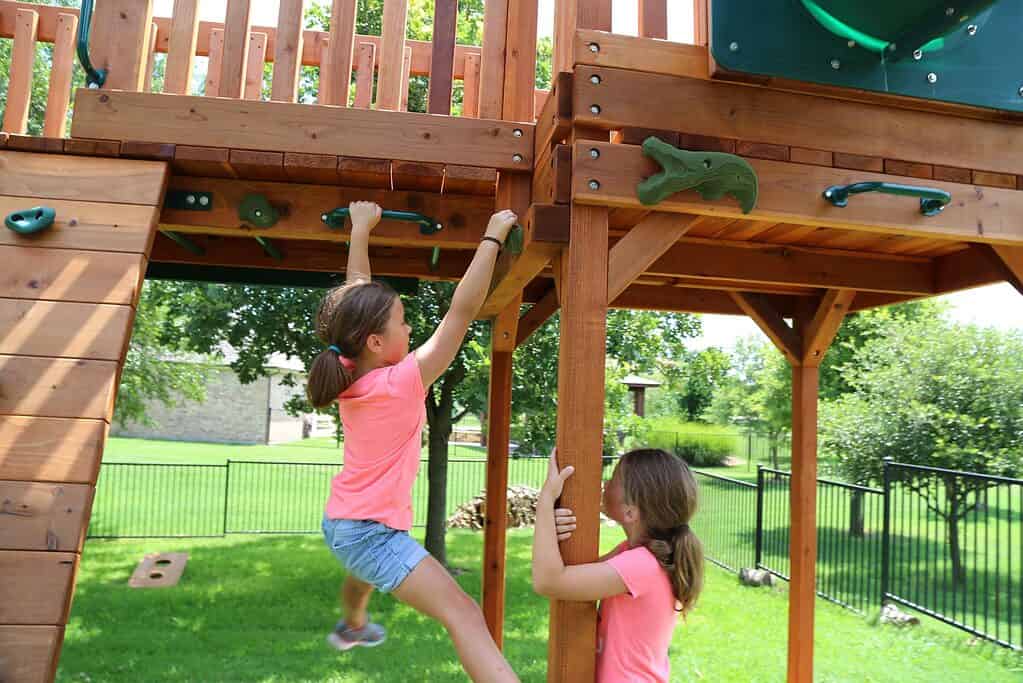 horizontal climbing rocks, ninja rocks with girl climbing around swing set