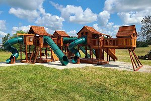 san antonio, texas, swingset deck height 7', customer playset shown with redwood playhouses bridged together with green slides, cabins, and bridges