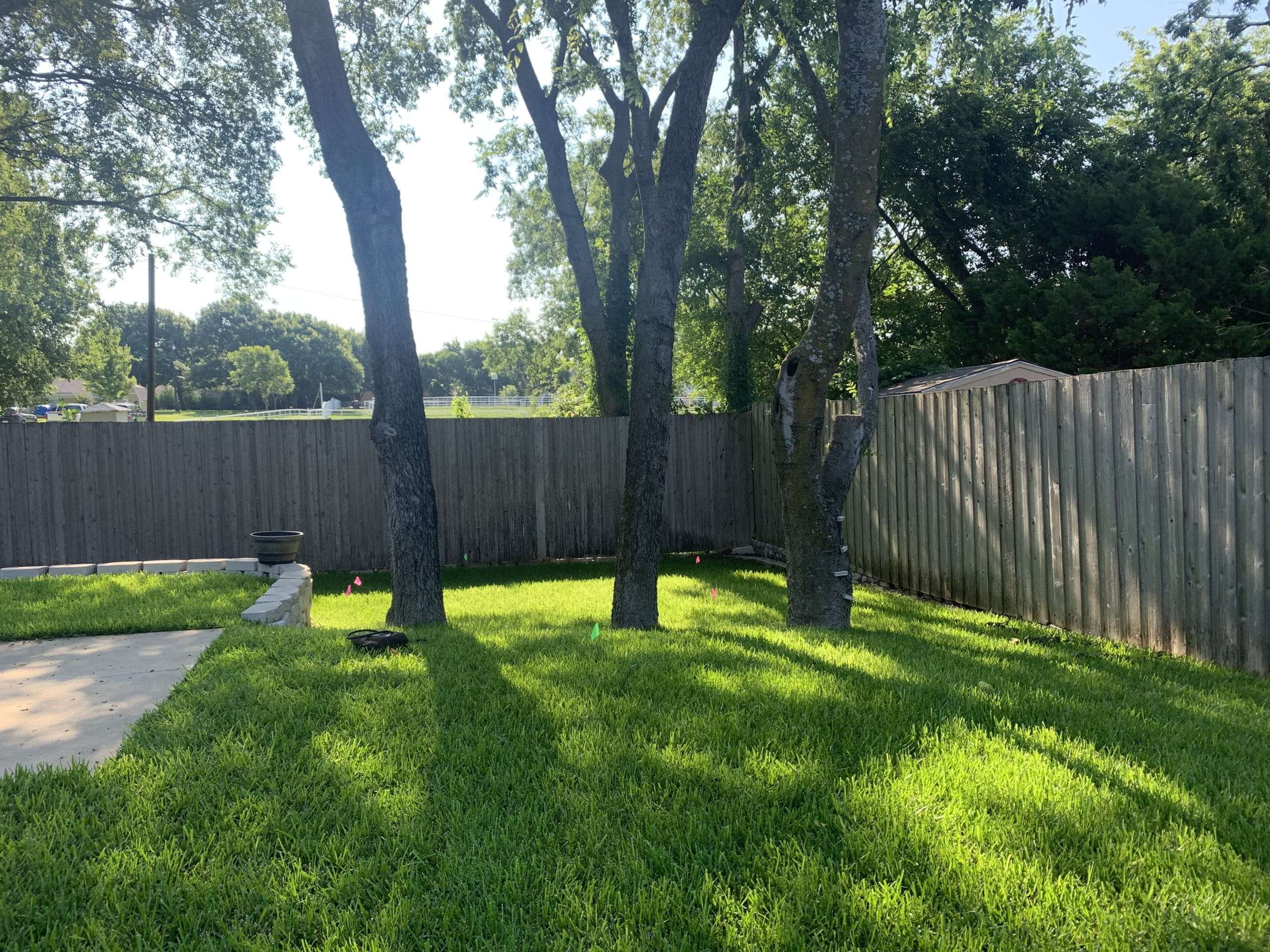 keller texas backyard with trees, slope and retaining wall for backyard swing set