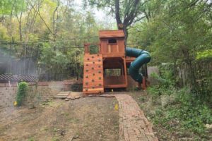 redwood custom playset customized for slope, retaining wall and power lines