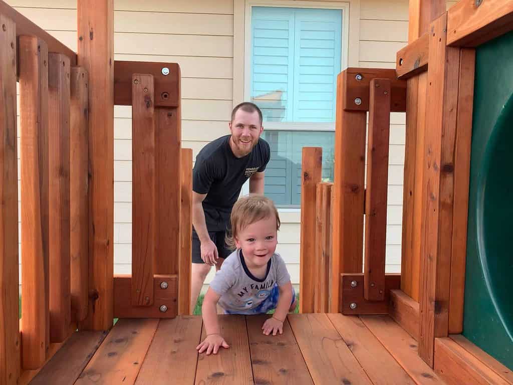 dad and son playing on redwood swing set