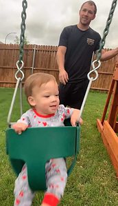 father and son enjoying family time on backyard swing set - wooden swing set