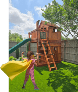Little girl in a yellow cape stands before her Backyard Fun Factory playset, pretend playing.