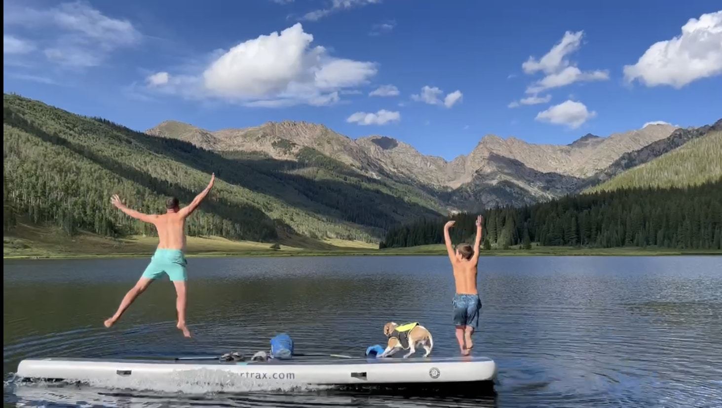 inflatable board with family jumping into lake from board.