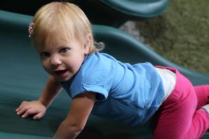 Joshua, Texas, toddler girl climbing on slide on backyard playset