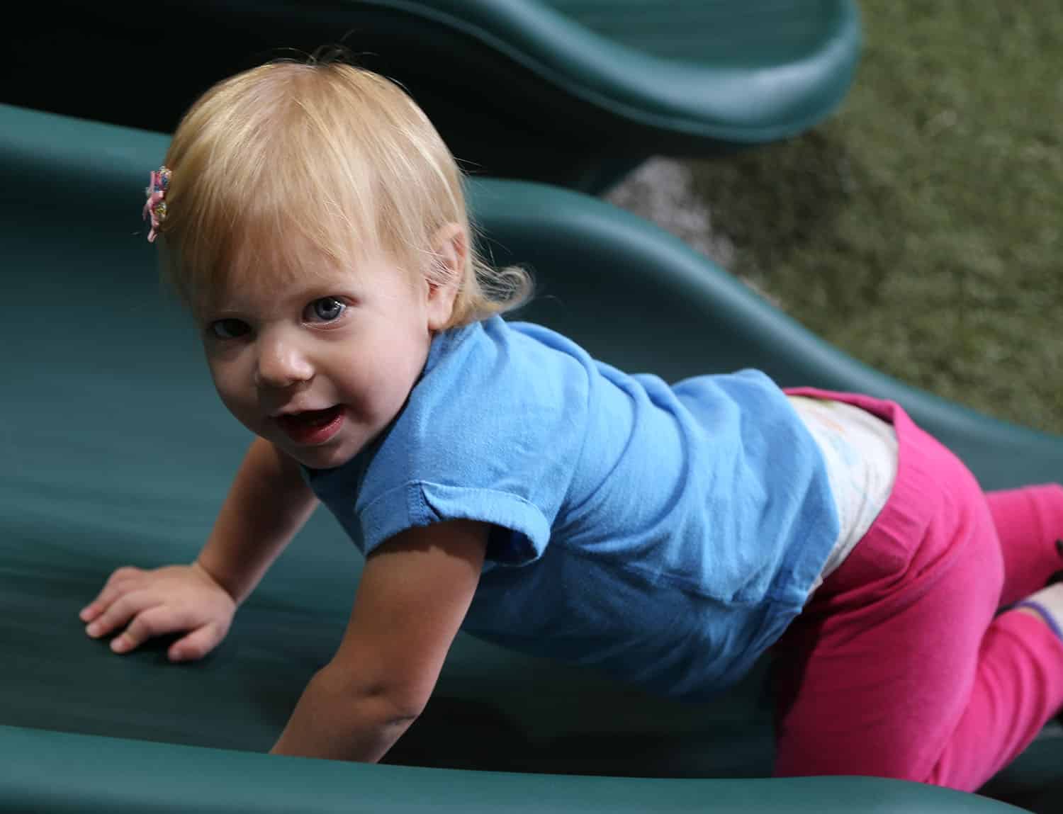 Joshua, Texas, toddler girl climbing on slide on backyard playset