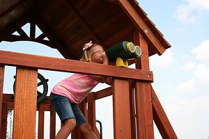 irving, texas girl with pink shirt looking through toy binoculars on backyard swing set