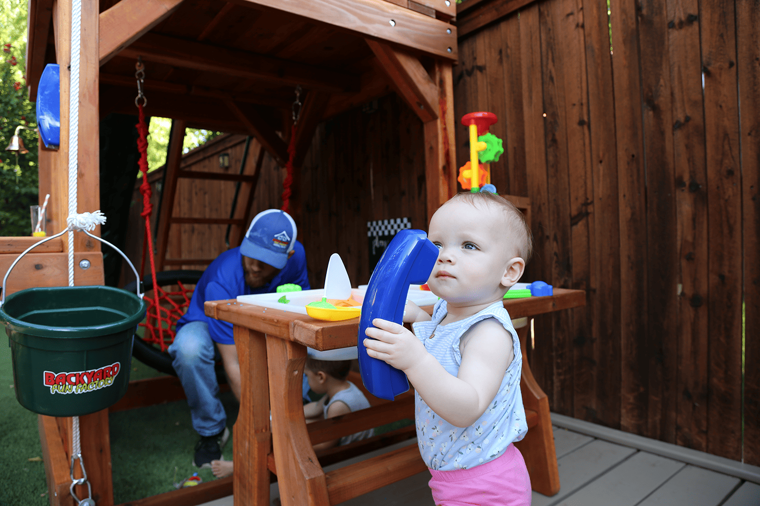 schedule time, lake worth, texas, little baby girl playing with blue toy telephone in backyard playset