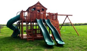 large redwood playset with rock wall and swings