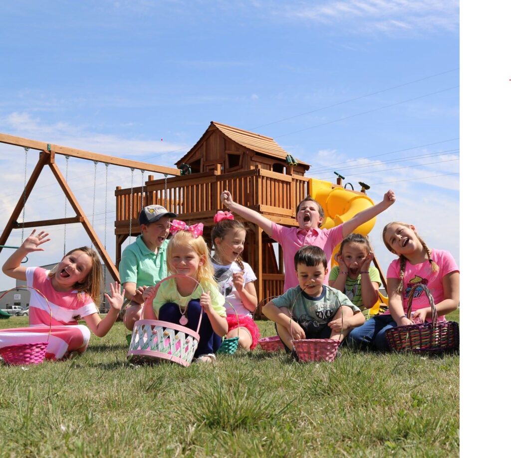 Children with their Easter baskets in front of a Backyard Fun Factory playset.