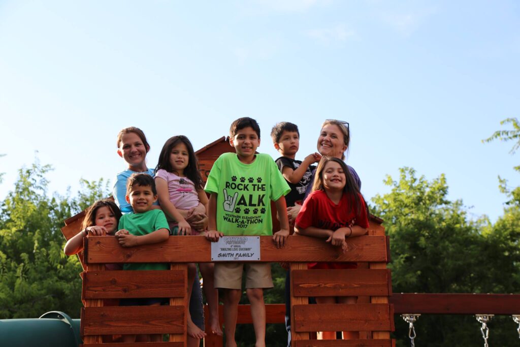 The winners of Backyard Fun Factory's Amazing Love Giveaway beam with joy as they stand atop their newly gifted Backyard Fun Factory playset."