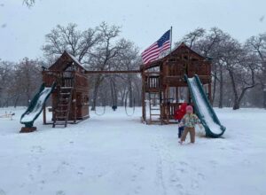Joyous Children playing on their expansive Backyard Fun Factory playset in the snow.