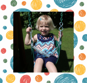 Joyful little girl on a whimsical Backyard Fun Factory swing.