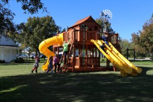 Children scattered over a Backyard Fun Factory playset, enjoying key aspects of child development, with the many benefits of a backyard playset.