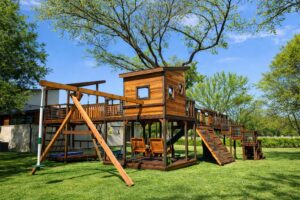 modern bridged swing set with adult chair swing, rock walls and bridges. Designed with metal conduit railing, square windows and straight slant roof.