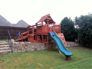 A uniquely landscaped backyard with a uniquely handcrafted Backyard Fun Factory playset.